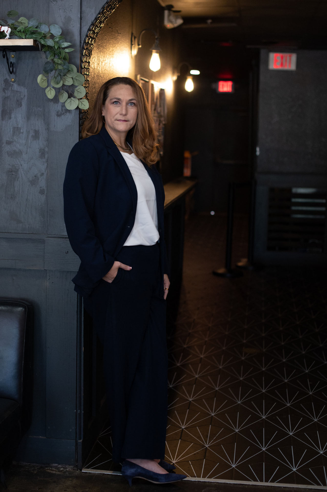 Joy St. John standing in a navy suit in a dim venue